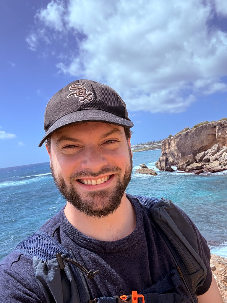 Zephan Johnson on a rocky coastline, wearing a Sox cap